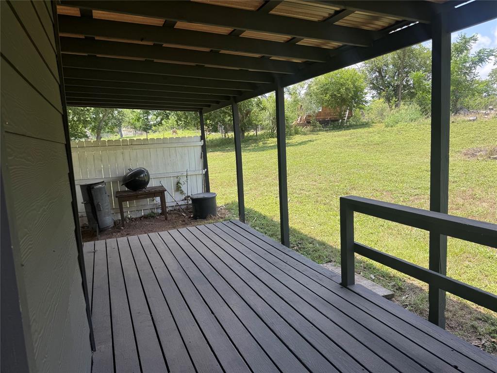 1825 East Pierce Street Luling, TX 78648 - Photo 12 of 16 A spacious covered deck extends to a verdant yard, offering a tranquil outdoor retreat.
