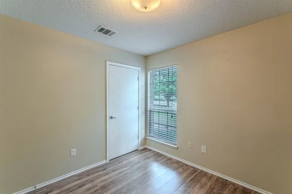 a view of an empty room with closet and a window