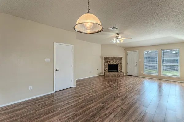 an empty room with wooden floor mirror and windows