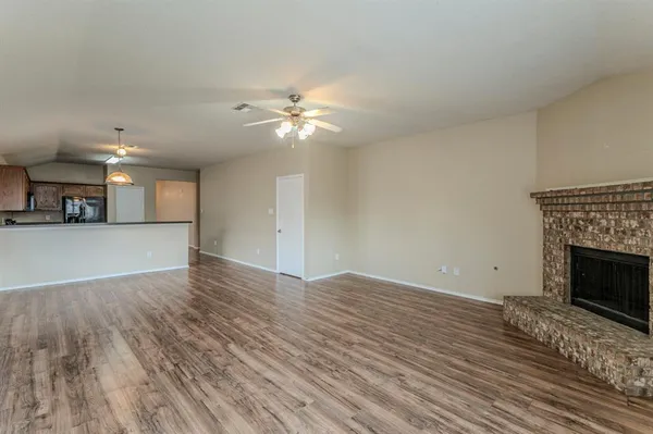 a view of a livingroom with a fireplace a ceiling fan and wooden floor