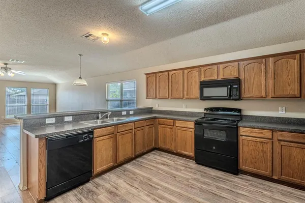 a kitchen with stainless steel appliances granite countertop a stove a sink dishwasher and a microwave oven with wooden floor