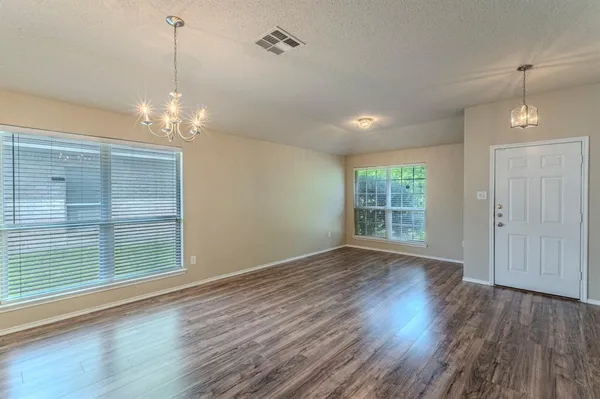 a view of a room with wooden floor chandelier and windows