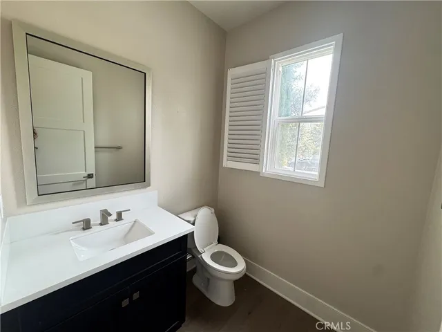a bathroom with a toilet a sink a mirror and a window