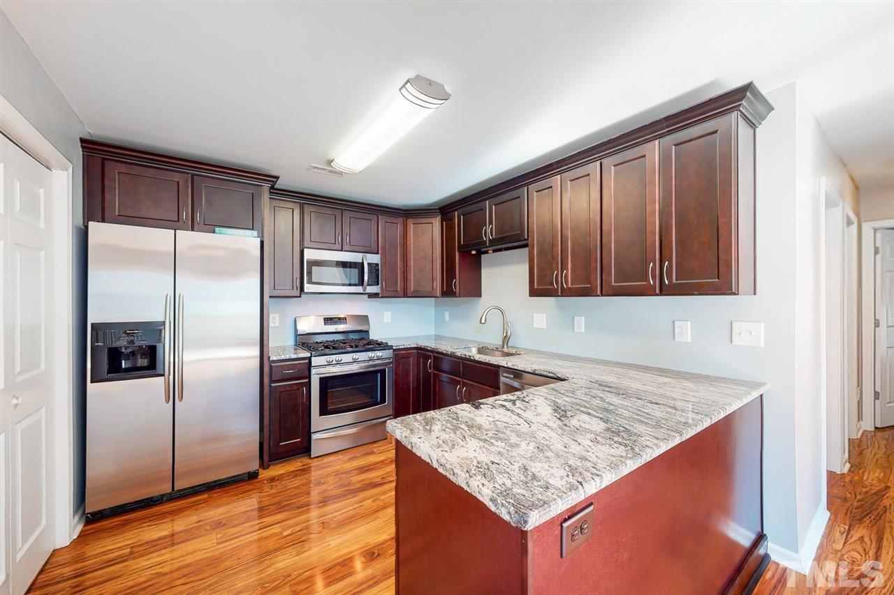 5309 Golden Moss Trail Raleigh, NC 27613 - Photo 10 of 25 a kitchen with stainless steel appliances granite countertop a refrigerator a sink a stove a microwave and island