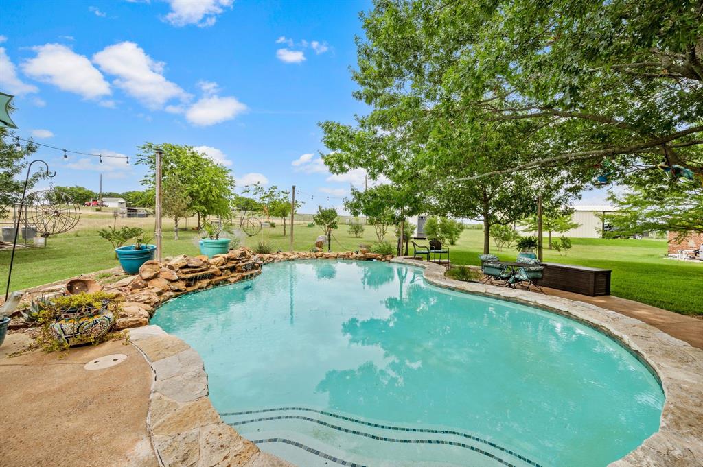 2141 Old Denton Road Decatur, TX 76234 - Photo 33 of 40 Freeform swimming pool featuring a rock waterfall, stone coping, and integrated steps