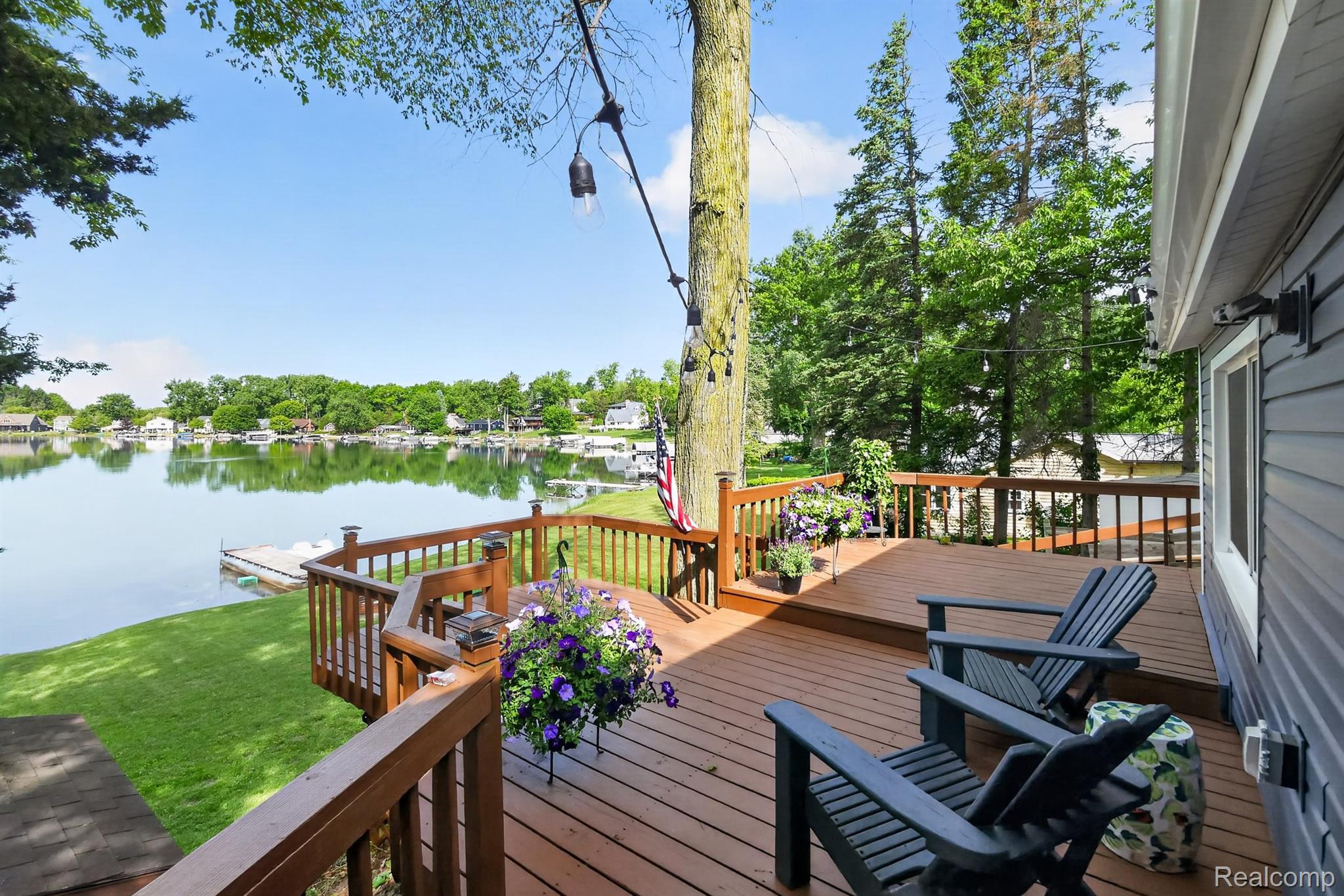 1717 Triangle Lake Road Howell, MI 48843 - Photo 8 of 58 Spacious wooden deck with lake frontage, featuring a brown railing and a grassy lawn leading to the water