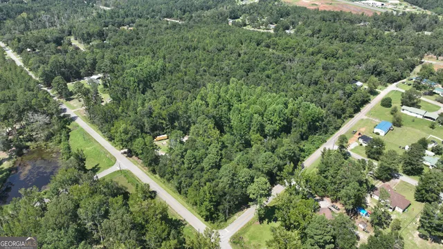 an aerial view of residential house with outdoor space and trees all around