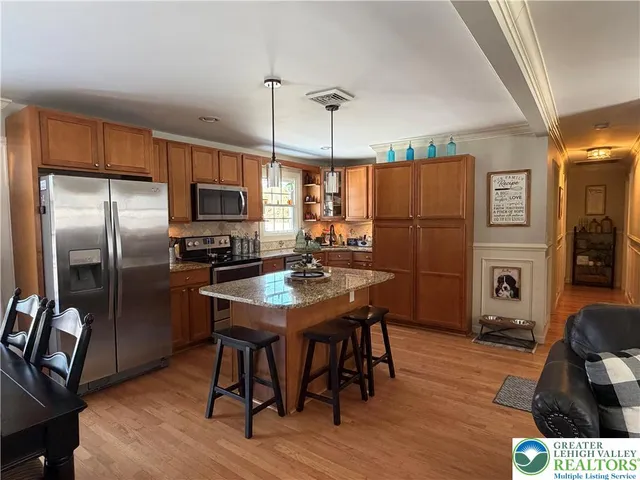 a kitchen with stainless steel appliances a refrigerator a stove a sink dishwasher a dining table and chairs with wooden floor