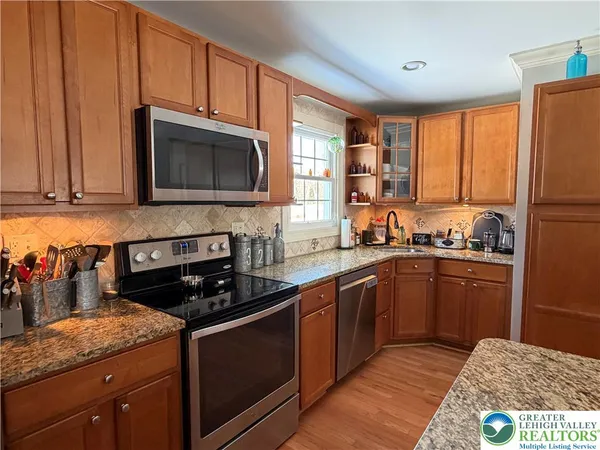 a kitchen with stainless steel appliances granite countertop a stove a sink dishwasher and a microwave oven with cabinets