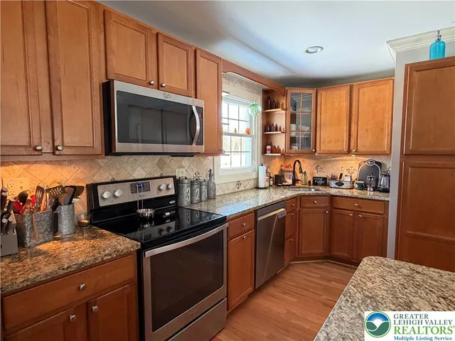 a kitchen with stainless steel appliances granite countertop a stove a sink dishwasher and a microwave oven with cabinets