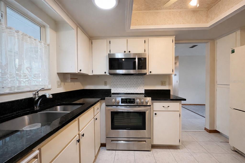11268 Southwest 75th Terrace Ocala, FL 34476 - Photo 23 of 32 a kitchen with granite countertop a stove sink and cabinets