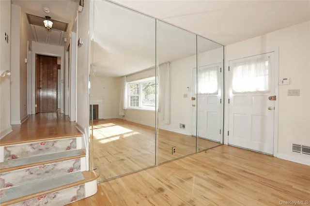 a view of an empty room with wooden floor and a bathroom