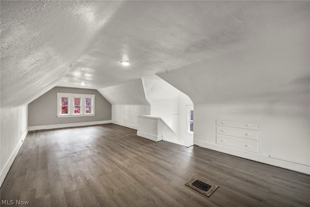 1677 Carlyon Road East Cleveland, OH 44112 - Photo 29 of 41 Additional living space featuring a textured ceiling, dark wood-style floors, lofted ceiling, and healthy amount of natural light