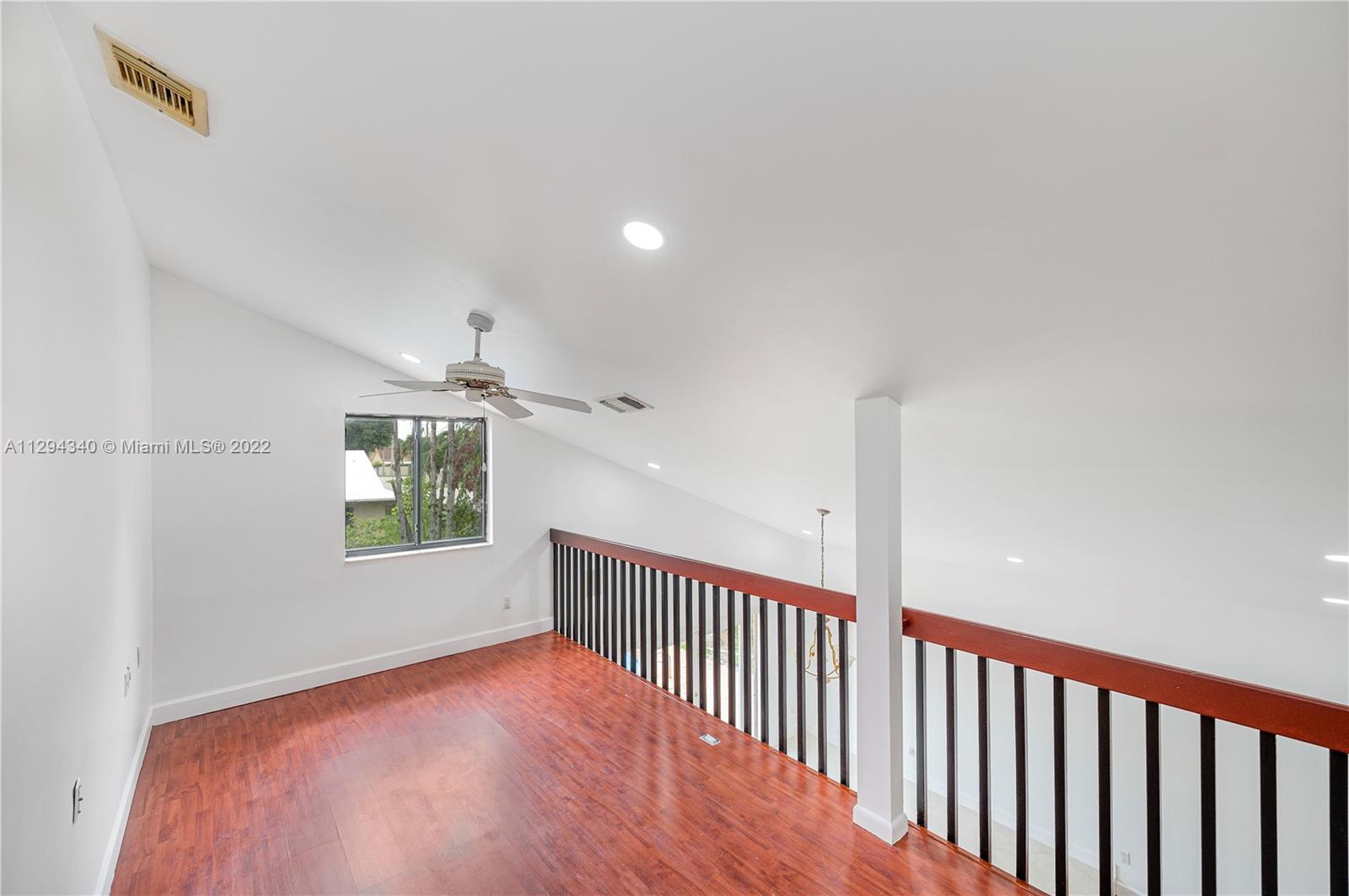 14442 Southwest 111th Street Miami, FL 33186 - Photo 11 of 15 a view of an empty room with wooden floor and windows