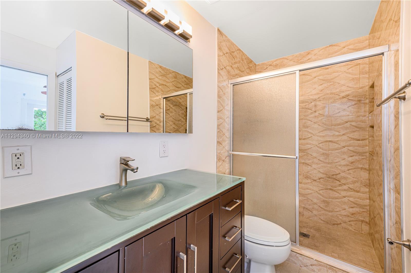 14442 Southwest 111th Street Miami, FL 33186 - Photo 10 of 15 a bathroom with a sink a toilet a mirror and shower