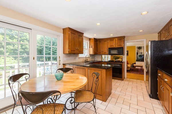 131 River Road Topsfield, MA 01983 - Photo 6 of 30 a kitchen with granite countertop a table chairs microwave and refrigerator