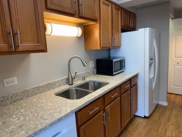 a kitchen with stainless steel appliances granite countertop a sink a refrigerator and a wooden cabinets