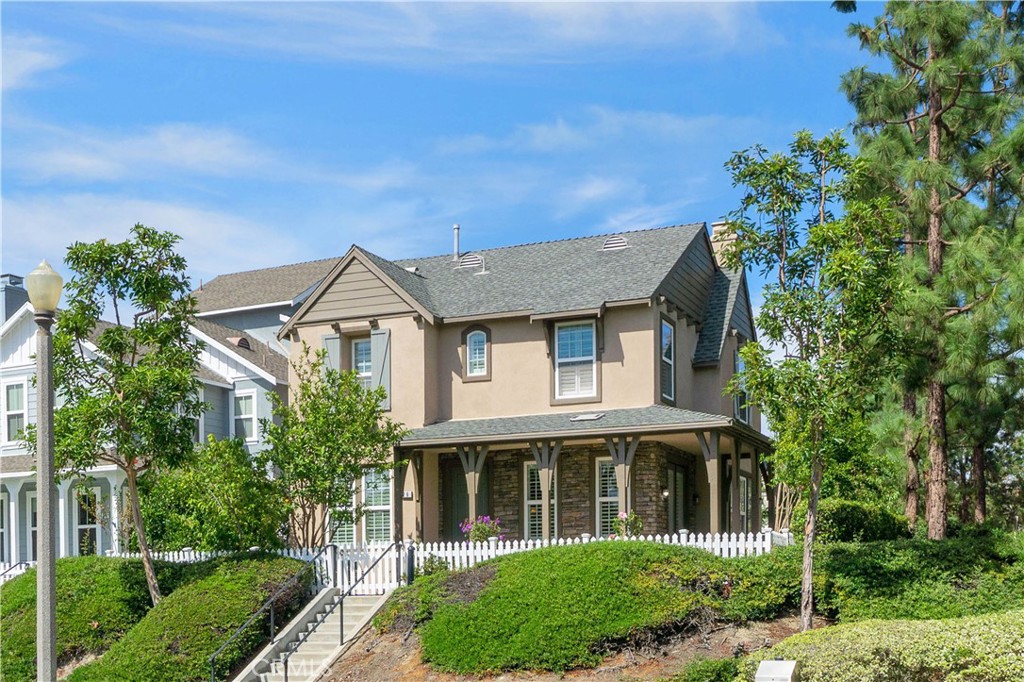 a view of a white house next to a yard with big trees