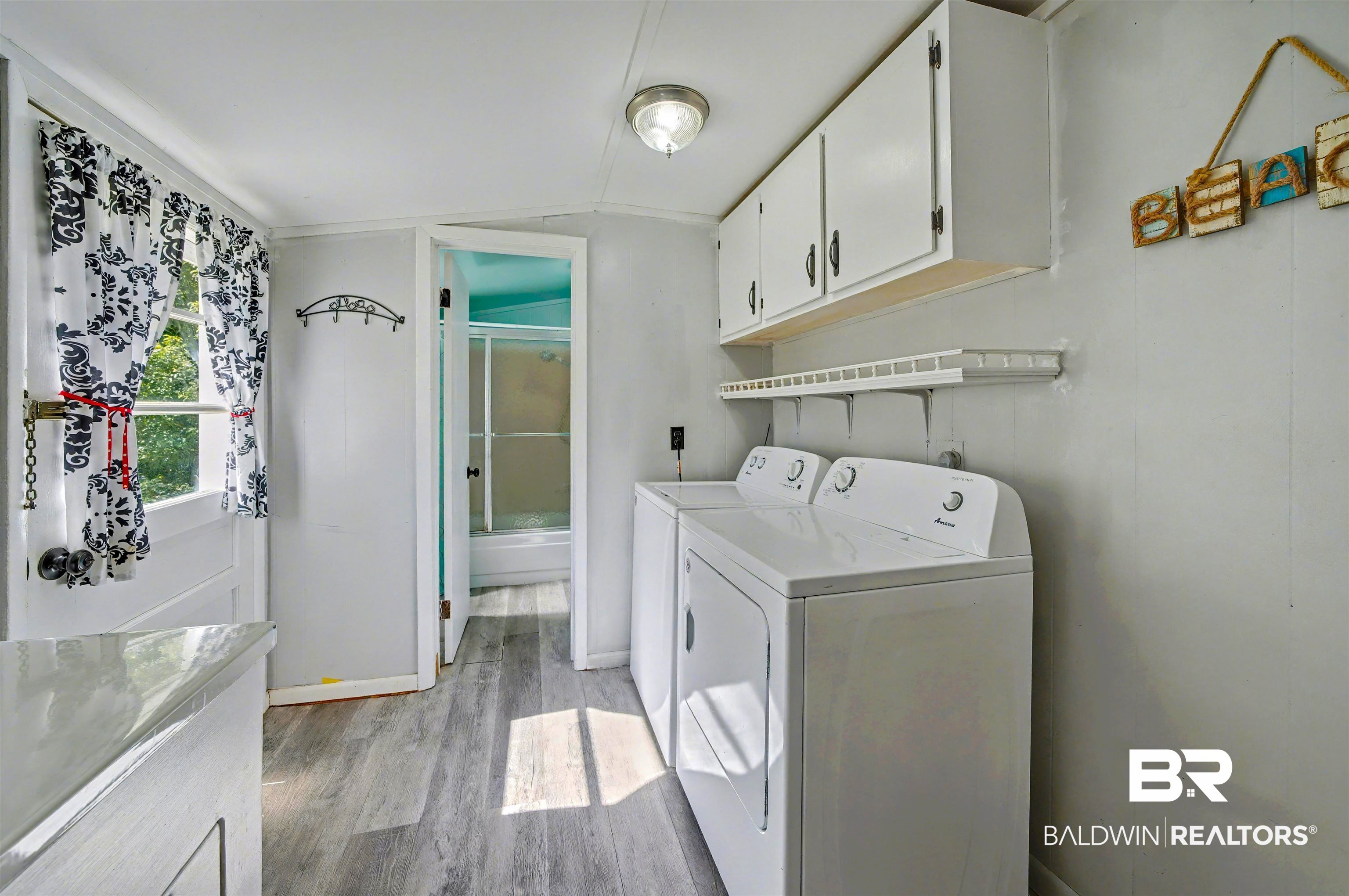 209 West Magnolia Avenue Foley, AL 36535 - Photo 21 of 23 Washroom with light wood-style flooring, lofted ceiling, cabinet space, and independent washer and dryer