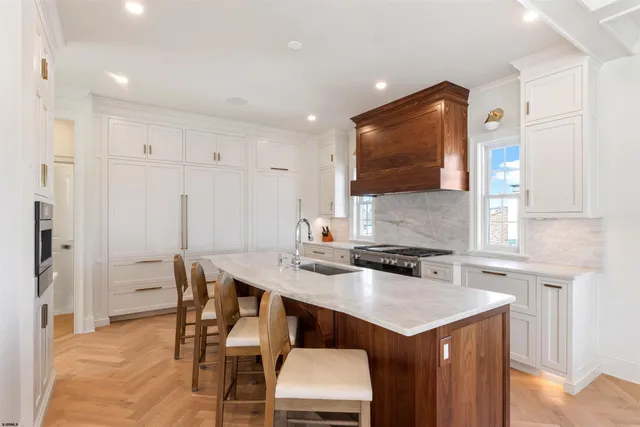 a kitchen with stainless steel appliances granite countertop a stove top oven a sink dishwasher a dining table and chairs with wooden floor