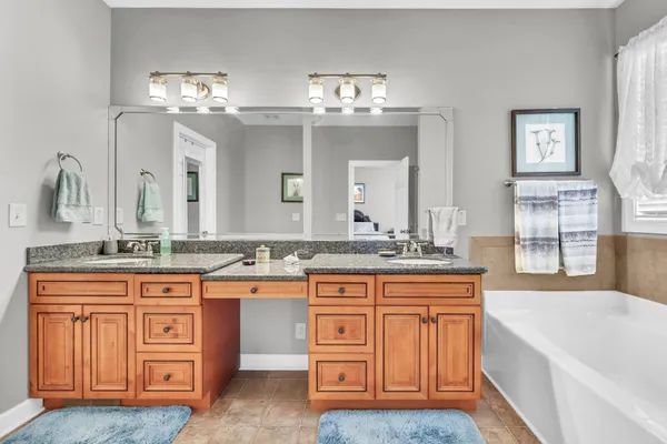 a spacious bathroom with a granite countertop double vanity and a large mirror