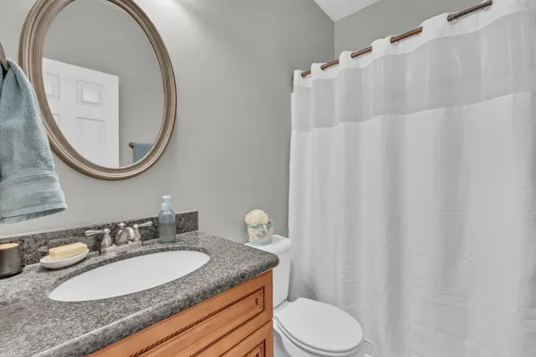 a bathroom with a granite countertop sink vanity mirror and toilet