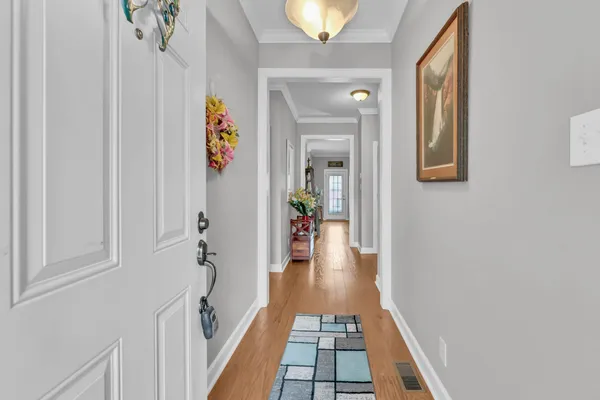 a hallway with painting on the wall and a potted plant