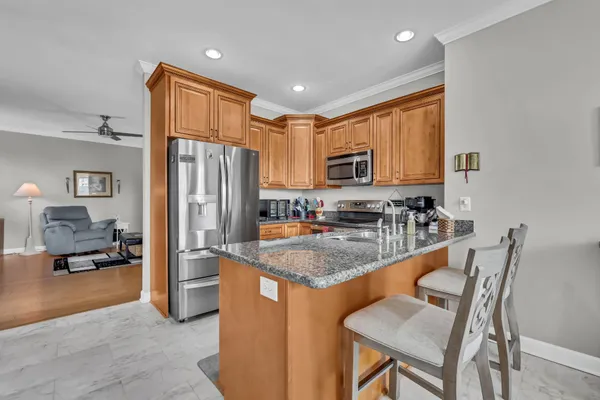 a kitchen with stainless steel appliances granite countertop a stove top oven a refrigerator a sink and a dining table with white cabinets