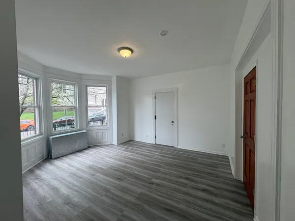 a view of an empty room with a window and wooden floor