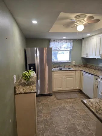 a kitchen with granite countertop a refrigerator and a sink