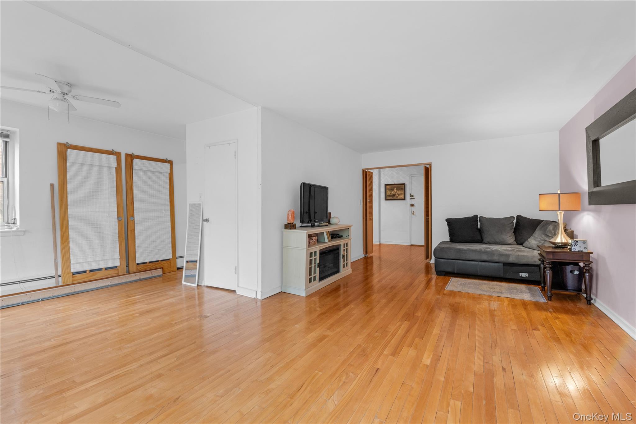 99-10 60th Avenue, Unit 3B Queens, NY 11368 - Photo 12 of 27 a living room with furniture and a wooden floor