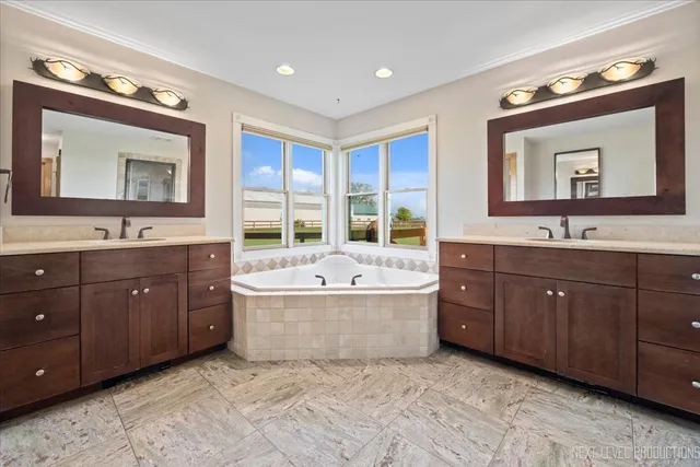 a bathroom with a granite countertop double vanity sink a mirror and a bathtub