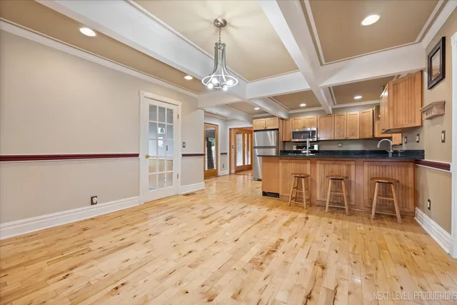 a kitchen with stainless steel appliances kitchen island granite countertop a refrigerator a stove a oven with white cabinets and wooden floor