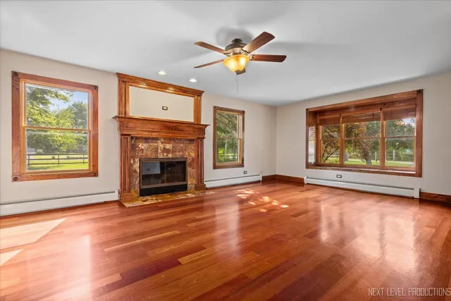 a view of an empty room with wooden floor fireplace and a window