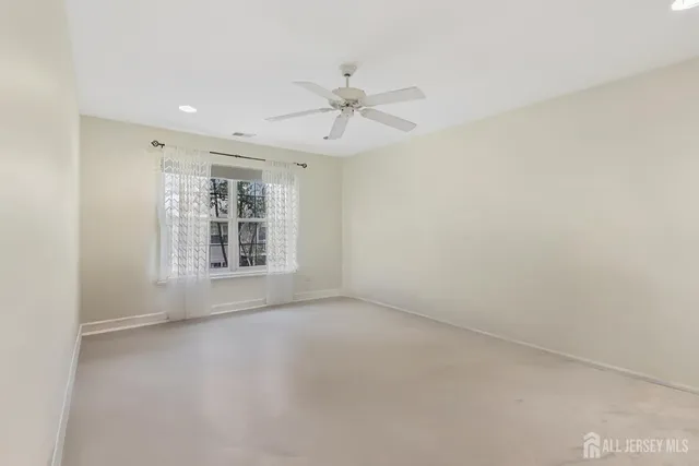 an empty room with chandelier fan and windows