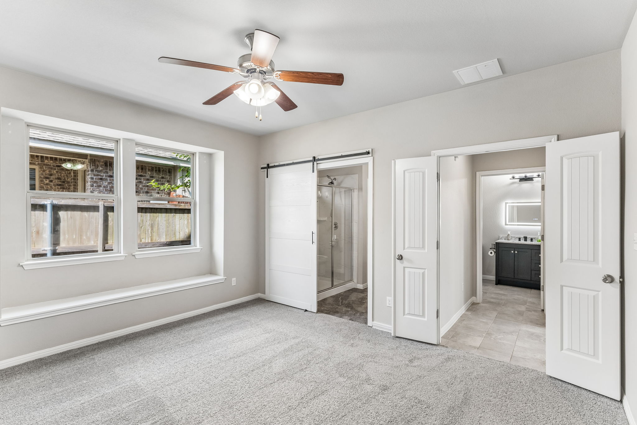 689 Nautical Loop Kyle, TX 78640 - Photo 15 of 34 A quiet retreat with plush carpeting and a modern ceiling fan, offering direct access to a private bathroom.