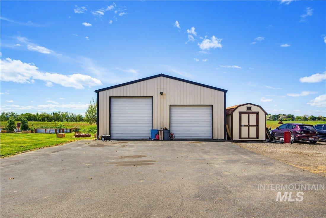 1901 South Ten Mile Road Meridian, ID 83642 - Photo 24 of 32 Two-bay metal outbuilding with roll-up doors, a separate storage shed, and a paved driveway surface