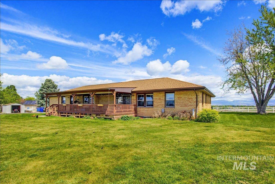 1901 South Ten Mile Road Meridian, ID 83642 - Photo 26 of 32 Expansive rear yard featuring a covered wooden deck, brick exterior, brown shingle roof, and distant mountain range