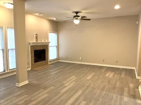 an empty room with wooden floor fireplace and windows