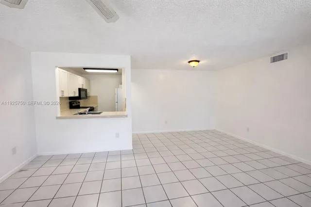 a view of an empty room and kitchen