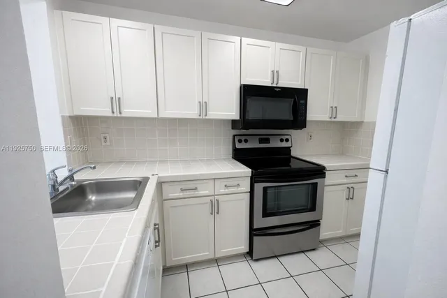 a kitchen with white cabinets and black appliances