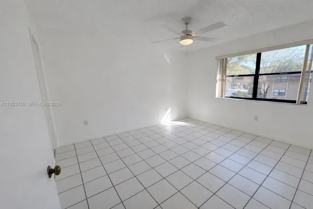 an empty room with windows and ceiling fan
