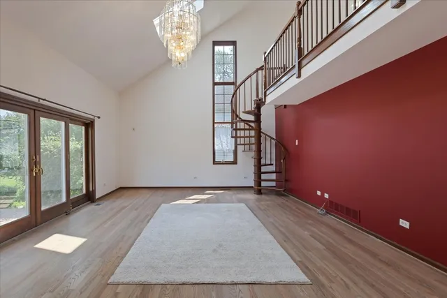 a view of an empty room with wooden floor and stairs