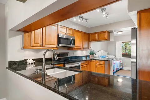 a kitchen with kitchen island granite countertop a sink appliances cabinets and a counter top space