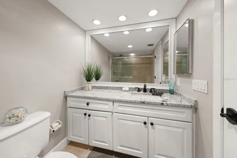 a bathroom with a granite countertop sink mirror and toilet