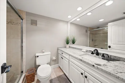 a bathroom with a granite countertop sink a large mirror and toilet