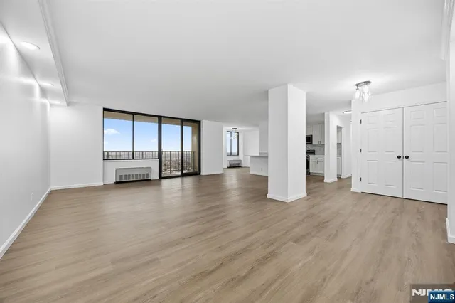 a view of an empty room with wooden floor and windows