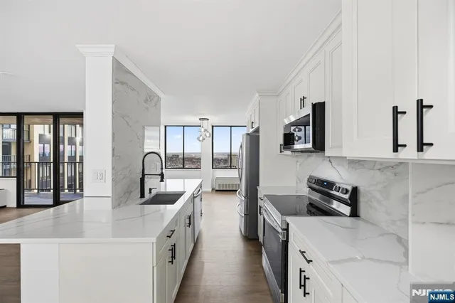 a large kitchen with stainless steel appliances granite countertop a sink and dishwasher a stove with wooden floor