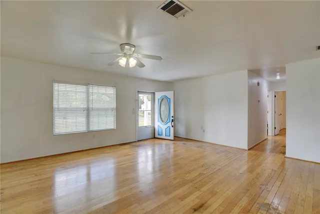 a view of an empty room with a window and wooden floor
