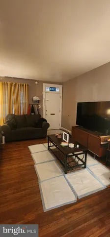 a living room with furniture a flat screen tv and a refrigerator